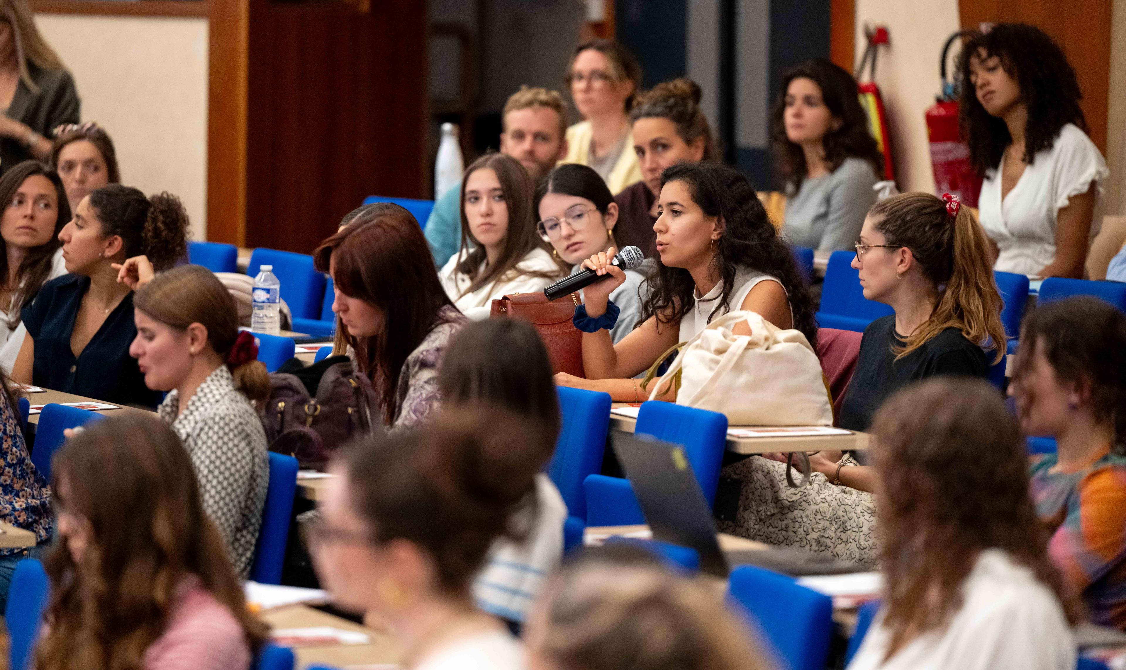 Jeune femme posant une question aux intervenants de la table ronde